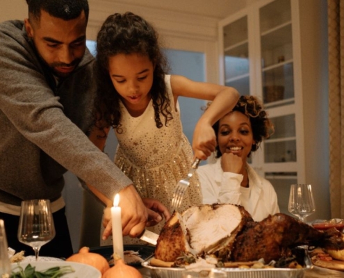 family carving turkey during holiday season - South Metro Custom Remodeling budget friendly basement ideas